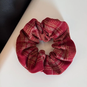 Detailed close-up of red plaid flannel fabric scrunchie with soft winter texture