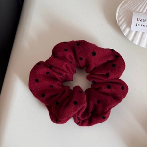 Nahaufnahme eines roten Polka-Dot-Haargummis auf einer weißen Muschelschale