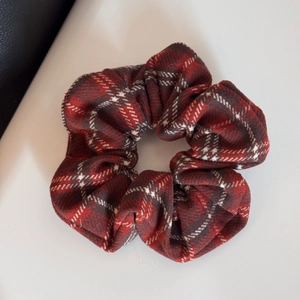 Detail of red plaid pattern and pleated fabric texture on classic scrunchie hair tie