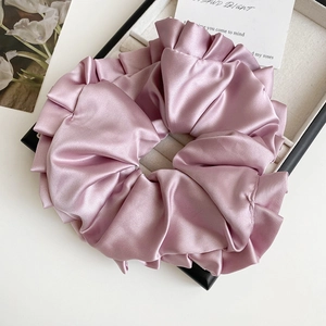 Détail d'un grand chouchou en satin rose avec texture en soie et plis élégants ondulés