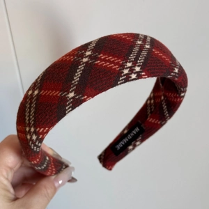 Detail of red plaid wool headband showing handmade woven label and thick fabric texture