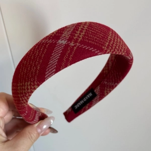 Macro detail of red plaid hairband featuring a handmade woven label and thick fabric