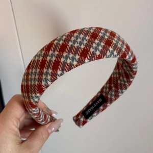 Close-up of red houndstooth knit headband with premium texture and handmade label