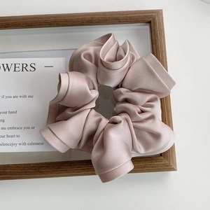 Chouchou plissé élégant en satin rose champagne avec une texture soyeuse et douce