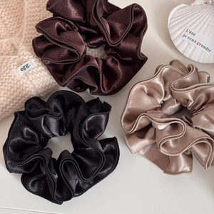 Three large satin scrunchies in black, chocolate and gold colors with ruffled edges