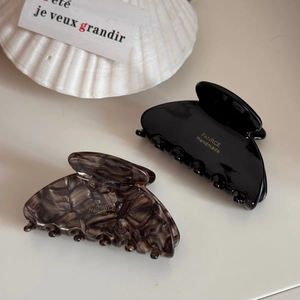 Detail of fan-shaped hair claws in black and tortoise shell with gold handmade logo