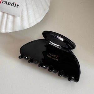 Detail view of glossy black resin hair claw clip with golden FANRCE handmade lettering