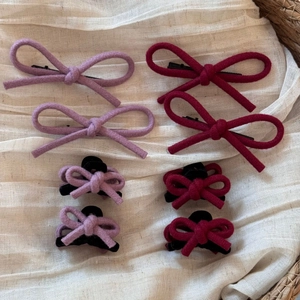 Détail de la pince à cheveux noeud en laine et petite pince sur tissu texturé