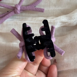 Vue détaillée de la petite pince à cheveux noire avec un nœud en feutre de laine mauve