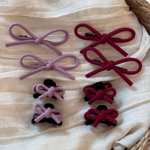Ensemble de barrettes à nœuds en velours rouge et lilas présentées dans un panier rustique