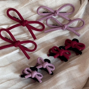 Ensemble de barrettes à nœuds en laine rouge et violette sur tissu beige doux