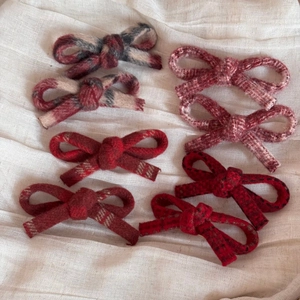 Detail view of woolen bow hair clips in various colors including plaid and solid tones