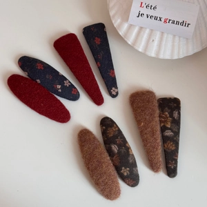 Détail de barrettes BB rétro en tissu floral et velours disposées sur un plateau