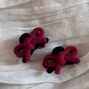 Détail de barrettes à cheveux noeud en velours rouge et noir sur un tissu blanc