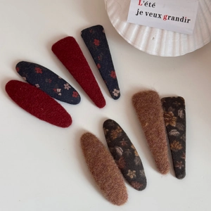 Vue à plat de barrettes BB en tissu vintage à fleurs avec une texture en laine