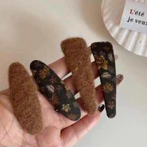 Détail de barrettes à cheveux en peluche à motif floral et marron pour look automne-hiver