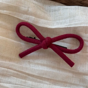 Détail macro du nɶud en velours rouge vin avec pince crocodile en métal noir robuste