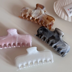 Detail of four acetate hair claws in tortoise shell, marble, and pink ink patterns