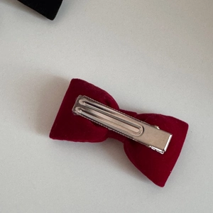 Dettaglio del retro di un piccolo fiocco di velluto rosso con base a becco d'anatra in argento