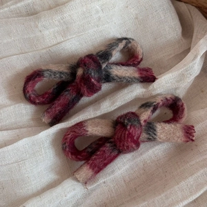 Macro detail of classic plaid wool bow hair clips showing textured fabric and knot detail