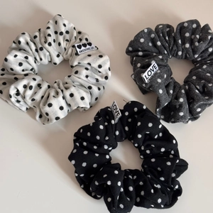 Detailed view of three polka dot fabric scrunchies in white, grey, and black patterns