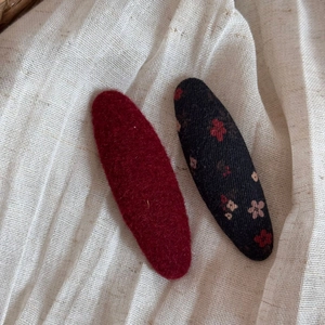 Détail de deux barrettes à cheveux vintage à fleurs et feutre bordeaux sur lin texturé