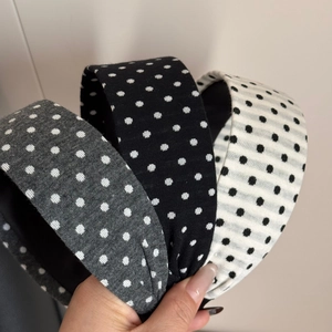 Detailed view of three wide polka dot headbands in black, white, and grey textured fabric