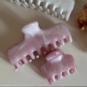 Detail of pink ink-patterned marble claw clips showing acetate texture and glossy finish