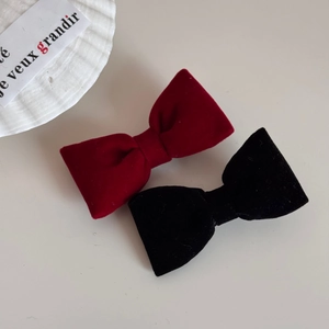 Dettaglio di eleganti fermagli per capelli in velluto rosso e nero su bianco