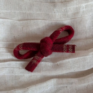 Macro shot of red wool bow hair clip with textured fabric on soft linen background