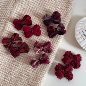 Détail de barrettes nœuds en laine rouge sur un fond de pull en maille beige doux