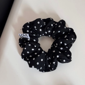 Detailed shot of black polka dot fabric headband with white Love From Seoul woven label