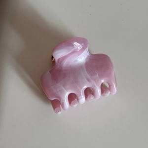 Close-up of pink and white marble ink texture on a glossy acetate hair claw clip