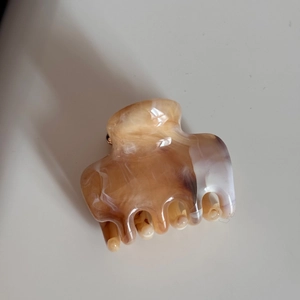 Detailed close-up of marble pattern hair claw clip with smooth amber and cream texture