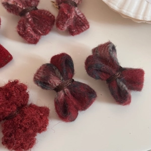 Vue détaillée de pinces à cheveux en laine rouge à nœuds avec une texture de tissu doux