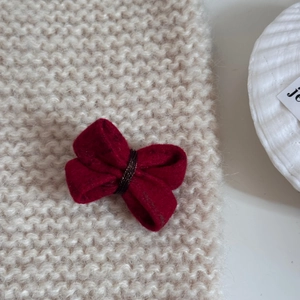 Gros plan sur la barrette nœud en feutre rouge avec cordon tressé à la main sur tricot