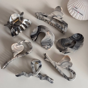 Flat lay of seven ink-washed marble pattern hair claws in minimalist French style