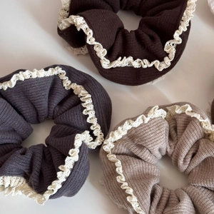 Detailed macro view of three knitted lace hair scrunchies in brown, gray, and khaki tones
