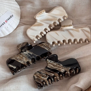 Detailed macro view of four marble patterned acetate hair claws in beige and black colors