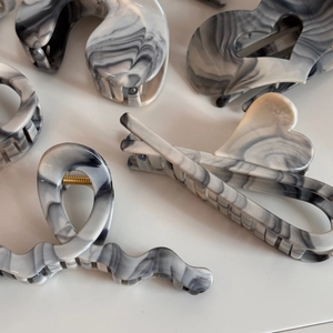 Detailed view of hair claws with grey and white marble ink patterns on white background