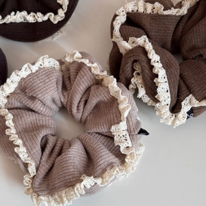 Detailed close-up of ribbed cotton scrunchies with elegant cream crochet lace edges