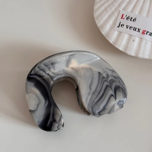 Detail of grey marble ink wash hair claw clip with acetate finish and glossy texture