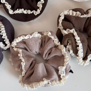 Detailed view of knitted hair scrunchies with white lace edges in earthy colors