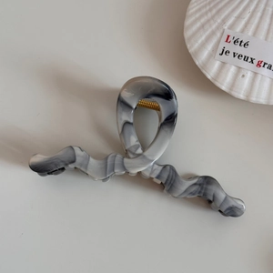 Detailed top view of the ink-wash marble acetate hair claw with gold metal spring