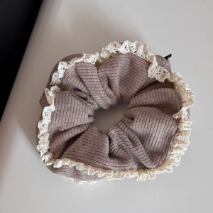 Detailed close-up of brown knitted scrunchie featuring vintage cream lace trim borders