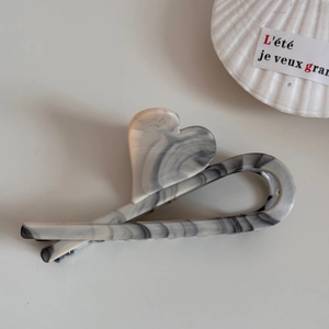 Close-up of marble pattern hair claw clip with heart accent on a cream background