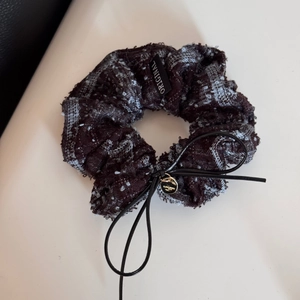 Detailed shot of tweed fabric hair scrunchie with leather bow and gold pendant