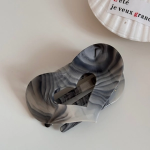 Macro detail of heart-shaped hair claw clip with grey ink marble texture and hollow design