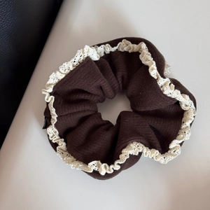 Detailed view of brown knit fabric and white crochet lace trim on the hair scrunchie