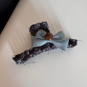 Detailed view of tweed fabric texture and satin blue bow hair clip accessory